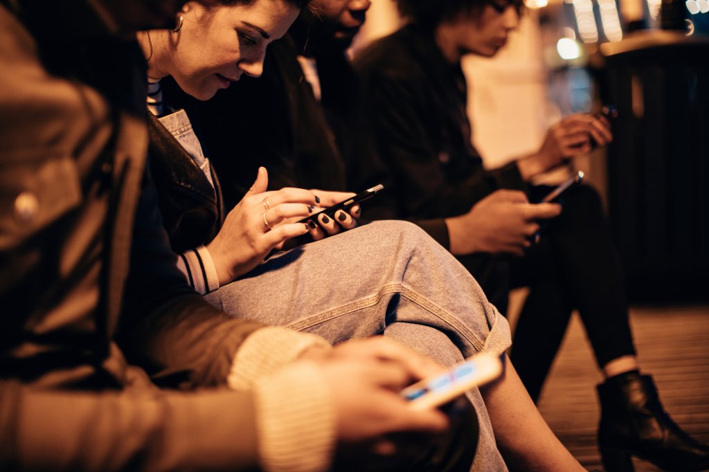 People sitting down and checking their phones.