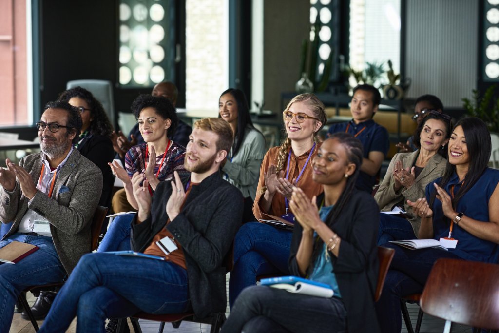 A group of people clapping at a conference to acknowledge the effective internal communications strategy.